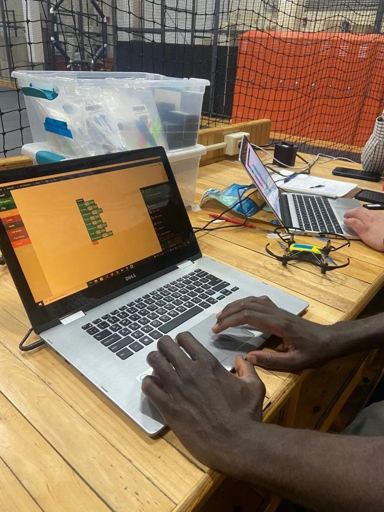 Students work on a computer to code a drone